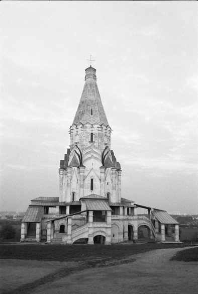 A black and white view of a white church, quite old, against a lightly clouded sky, nobody about.