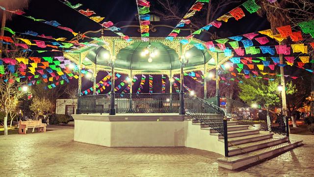 a photo of a kiosk during the night, which has colorful ornamental papers used typically around the kiosks in small villages as a meeting point.