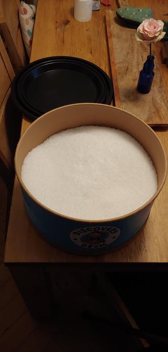 Photo of large cardboard drum shaped tun full of tiny polypropylene beads, placed on a wooden table