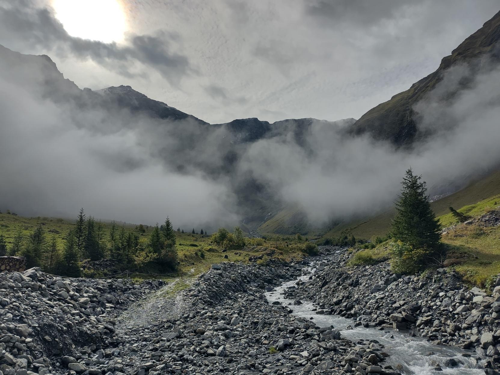 Foggy mountain landscape with a stream flowing in a stony riverbed