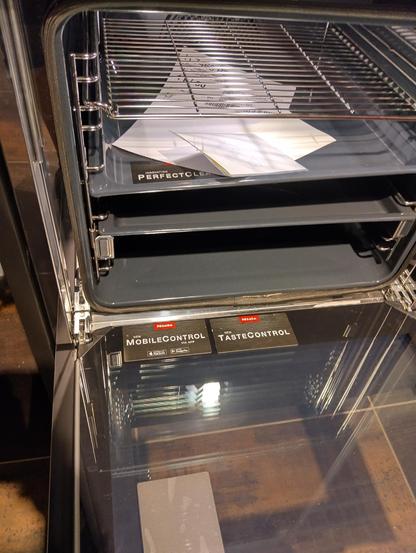 photo of an open oven door with a sticker that says "mobile control" and symbols for apple and Google playstores