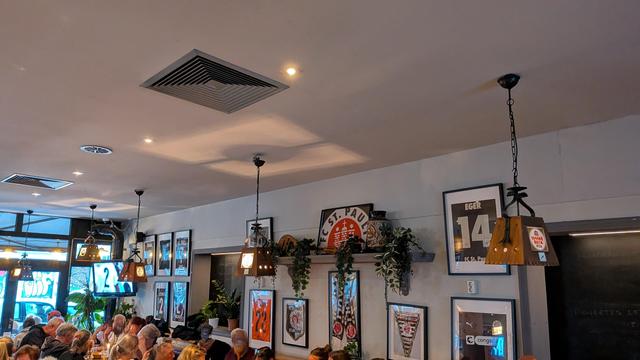 Eingerahmte Trikots von aktuellen und ehemaligen Spielern. Gäste sitzen an Tischen.