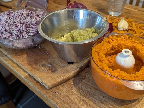 Drei Schüsseln mit roten Zwiebeln, Staudensellerie und Möhren, jeweils fein gewürfelt bzw gehackt