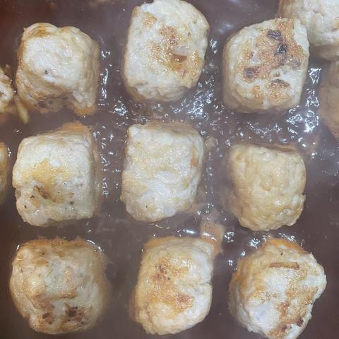 Homemade meatballs simmering in sauce, these are decidedly cuboid from how they were turned during frying - here nine laid out in a grid