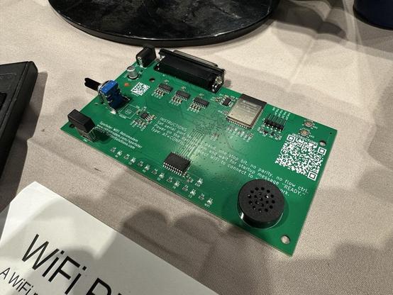 Photograph of a sparsely populated circuit board with a speaker, serial port, adjustable potentiometer, button, wifi radio, and five small ICs. The words "INSTRUCTIONS: Set serial port to 9600 baud, one stop bit, no parity, no flow ctrl. Power on the Retromodem and wait for startup message "READY". Type AT+CONFIG and select WiFi to connect to wifi network."