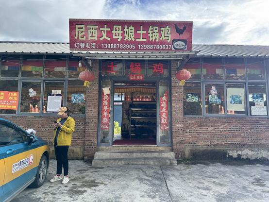 The outside view of the hotpot restaurant, with a sign saying “尼西丈母娘土锅鸡”.