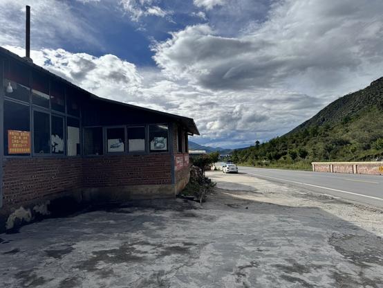 The roadside view of the hotpot restaurant, somewhere on a country mountain road, with clouds in the distance.