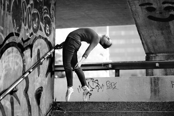 Ballerina auf dem Absatz einer Außentreppe auf Spitze stehend und nach hinten gebeugt