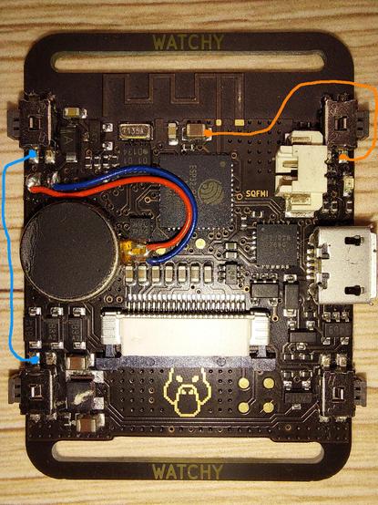 Photo of the circuit board of a Watchy v1 ePaper smart watch. On top of the photo, an orange and a blue line have been drawn to illustrate connections to be made.