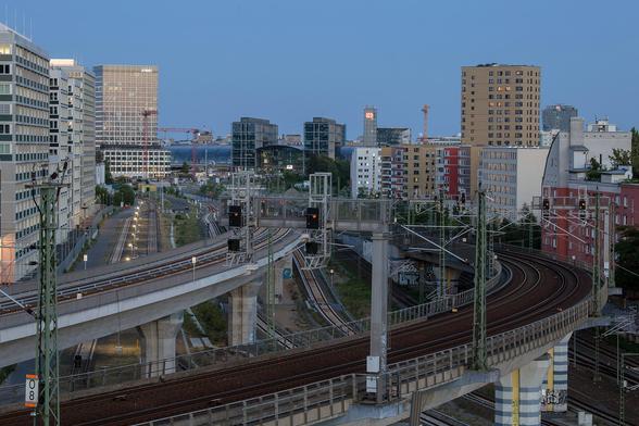 Blick auf erhöhte Eisenbahngleise mit Signalanlagen in Berlin, im Hintergrund moderne Büro- und Wohngebäude sowie der Berliner Hauptbahnhof.