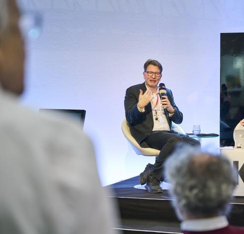 Der Galerist und Beiratsvorsitzender der art Karlsruhe Kristian Jarmuschek sitzend auf dem Podium mit Mikrofon. Rechte: Carlotta Roob/Messe Karlsruhe