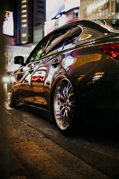 photo of the rimas and the side of a BMW tuning car parked during the night at the famous Shibuya crossing in Tokyo