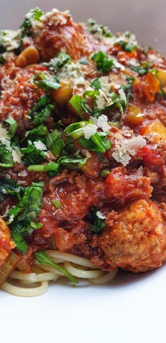 A bowl of Spaghetti Bolognese w/ soy mince & balls. Topped w/ fresh basil & yeast flakes.