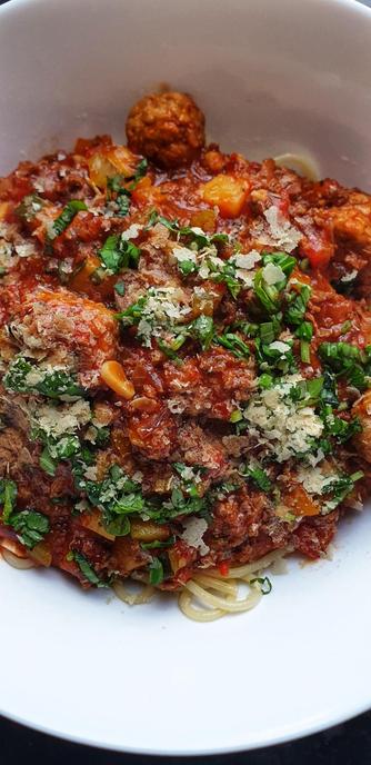 A bowl of Spaghetti Bolognese w/ soy mince & balls. Topped w/ fresh basil & yeast flakes.