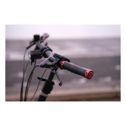 Nahaufnahme des Lenkers. Die Enden der Griffe schimmern rot metallisch wie auch die Pedalen