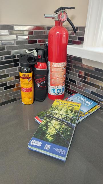 A kitchen counter with bear spray, fire extinguisher, and local maps.