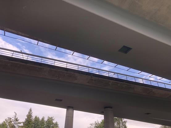 Unter nebeneinander verlaufenden Brücken nach oben fotografiert. Im Spalt zwischen den Straßen ist blauer Himmel.