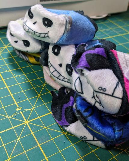 a stack of empty pocket plush shells, faces all squished as they wait to be stuffed
