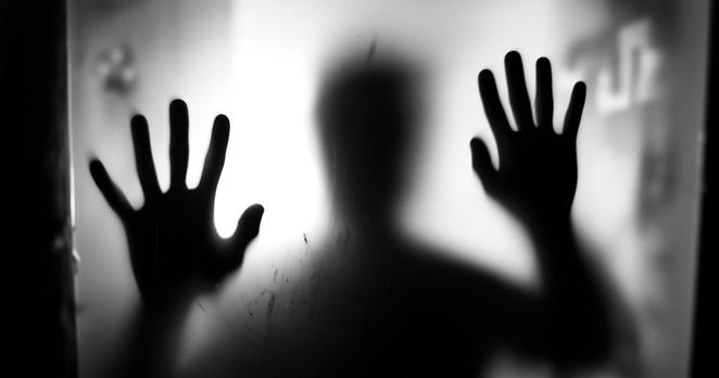 Silhouette floue d’une personne derrière une vitre opaque, les deux mains appuyées contre la surface — une image évoquant la peur, l’angoisse et l’emprise de l’alarmisme médiatique.