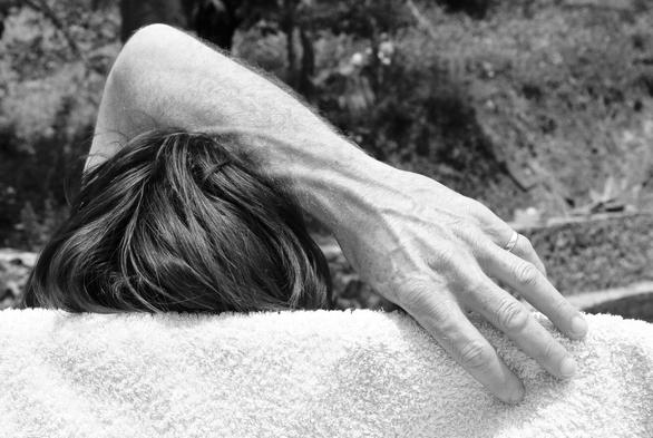 From behind, the head of someone napping on a deck chair with an arm over it to protect er eyes. (Version françæ) Vux de dos, læ tête avec æn bras par dessus pour protéger les yeux d’æn personne qui fait læ sieste sur æn chaise lonx.