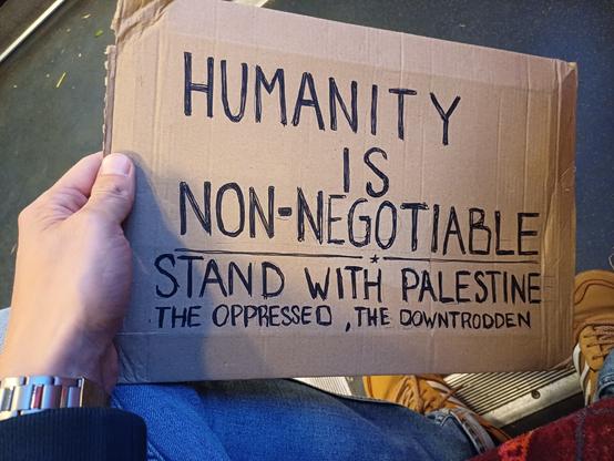 A plackard held up at the show saying "Humanity is non-negotiable", "Stand with Palestine, the oppressed, the downtrodden".