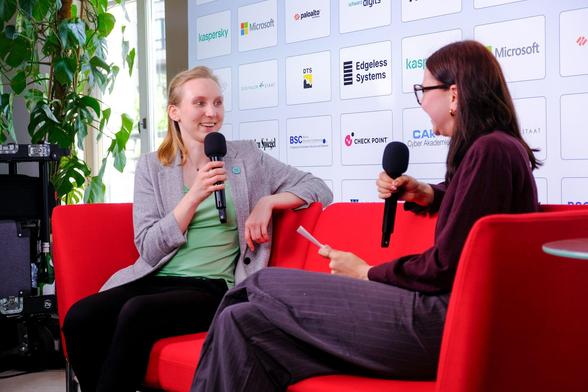Dr. Lea Beiermann und Mirjam Klinger sitzen auf einem roten Sofa. Beide halten Mikrofone in der Hand.