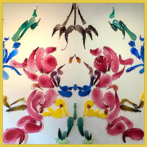 colorful glass objects mounted to a wall. It seems a mirrored image, like a Rorscach plate.