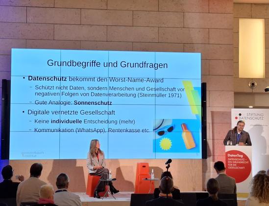 Bock und Rehak auf der Bühne. Folie mit Grundbegriffen und Grundfragen des Datenschutz zu sehen:

Datenschutz bekommt Worst-Name-Award
- Schützt nicht Daten, sondern Menschen und Gesellschaft vor negativen Folgen von Datenverarbeitung (Steinmüller 1971)