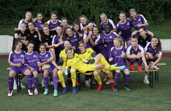 Team-Foto der Essener U17, die in drei Reihen hintereinander steht und sitzt, alle sind absichtlich schief, lachen, ziehen Grimassen oder zeigen lustige Gesten. Freutel hat die Arme sehr hoch verschränkt und die Mundwinkel übertrieben nach unten gezogen, Malinowski macht eine Mischung aus Zunge rausstrecken und Peace-Zeichen, Längert hat einen Arm lachend um eine der Spielerinnen gelegt. Von den drei Torhüterinnen im Vordergrund hat sich eine quer über die beiden anderen gelegt, die auf einer Bierbank sitzen.