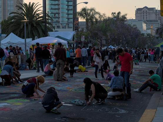 People on a closed street using chalk to make art on the road
