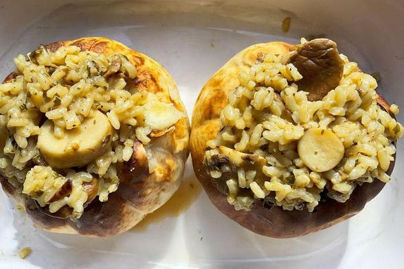 Two small seasonal squashes stuffed with mushroom risotto and herbs, baked to a golden brown, served in a white dish.