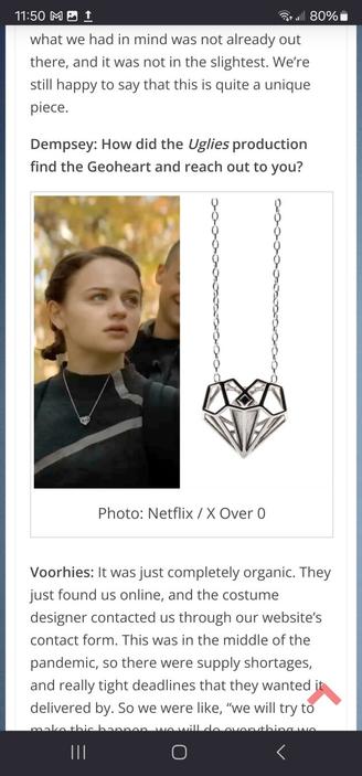 Screenshot from the Comicon.com article interviewing Xover0 about their necklace design featured in the Netflix movie Uglies. The article's image shows a still frame of lead actor Joey King wearing Xover0's heart-shaped silver pendant, side by side with a close-up of the necklace on a white background.