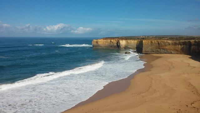 Meer, Strand und Himmel. Im Hintergrund ein Felsen.