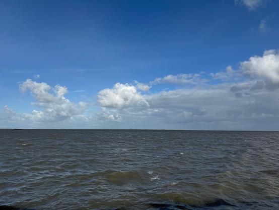 The North Sea under a blue sky with some clouds. Waves are on the water.