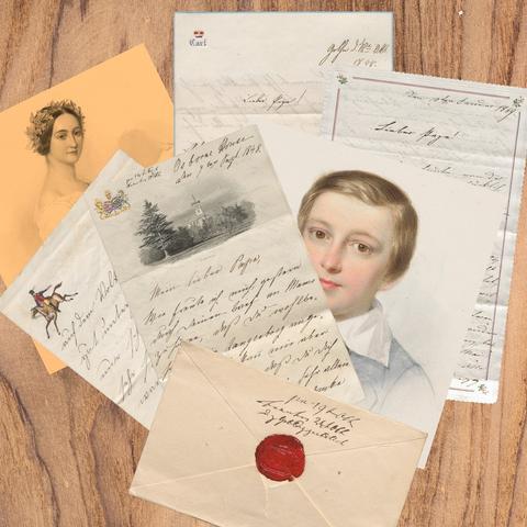 Auf einem Holztisch liegen, zum Teil überlappend, mehrere Originalbriefe des 19. Jahrhunderts, die Prinzessinnen und Prinzen des Hauses Hohenlohe als Jugendliche und junge Erwachsene geschrieben haben und ein Briefumschlag mit Siegel.