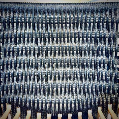 A blue woven pattern comprising the seat of a chair fills the frame from bottom to top.