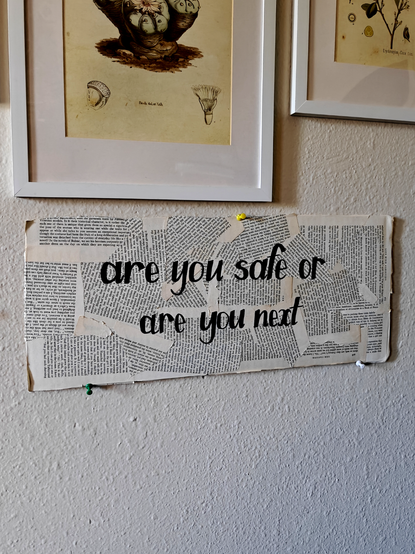 art panel hanging on my wall, covered with old torn book pages and emblazoned w handlettered black words: 

are you safe or are you next