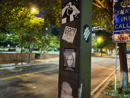 A pole that has many stickers including one commemorating Scout Schultz