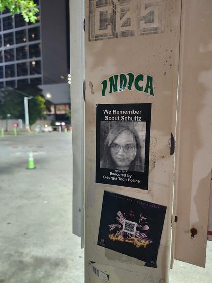 A pole that has many stickers including one commemorating Scout Schultz