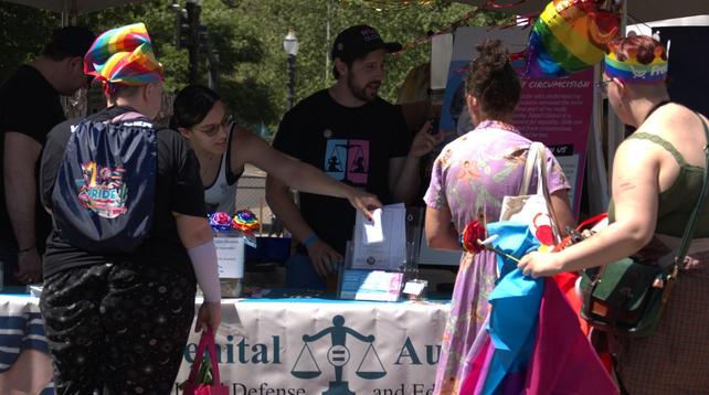 Alliana (left) setting out literature at the Portland Pride 2025 GALDEF booth.  Eric Clopper of Intact Global talking to a woman on the right.
