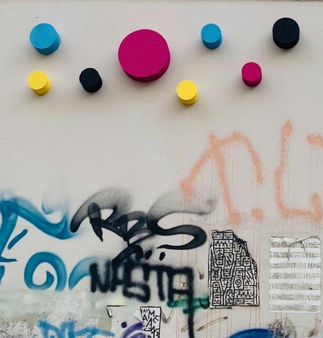 Hauswand mit Graffiti und dreidimensionalen Kreisen in Zyan, Magenta, Gelb und Schwarz.