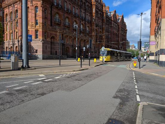 A tram passes red brick buildings