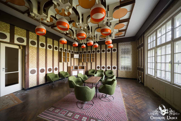 retro hotel room. Table with green chairs around. From the ceiling hang 1970s retro lamps