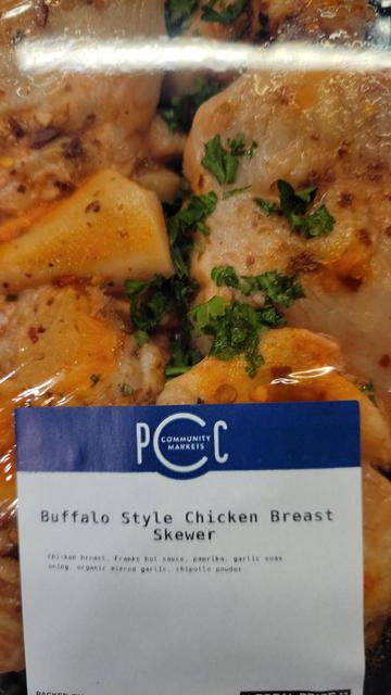 A shrink wrapped ready to cook package of chicken beat meat skewers. The PCC label reads "Buffalo Style Chicken Breast Skewers"
