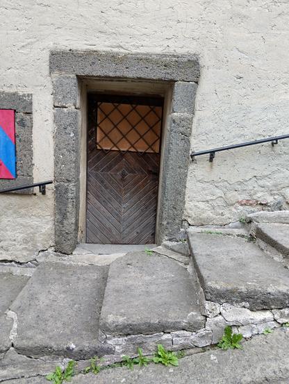 a small wooden door in a stone wall behind some stone steps