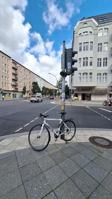 Ein weißes ein weißes Fahrrad ist an einer Fußgängerampel direkt im Weg der Fußgänger mit Blindenleitstreifen so angeschlossen, dass es Fußgänger behindert und Sehbehinderte sogar gefährdet.

 Die Abstellweise ist  unverantwortlich und zu bestrafen.