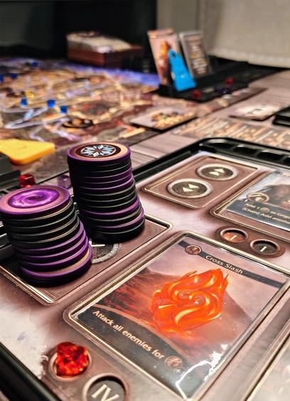 Nahaufnahme vom Teil eines player boards aus The Isofarian Guard. Im Bereich für die benutzen Chips stehen zwei Stapel aus schwarzen und violetten Chips, jeder gut ein dutzend Chips hoch