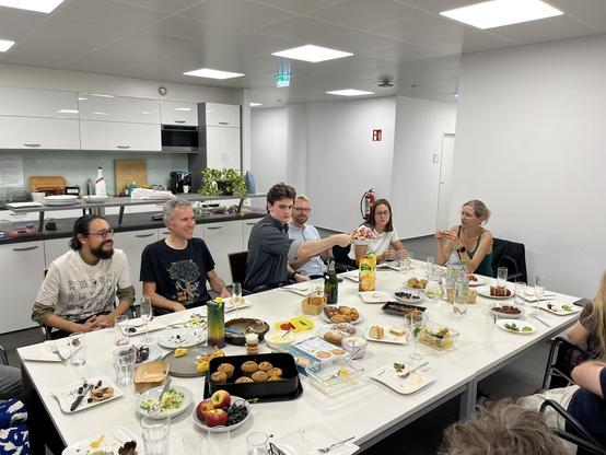 Group gathering around a table. People eat and pass around dishes.