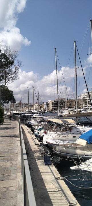 Pieta Marina, central Malta...rows of small yachts and house boats are moored under white fluffy clouds and a blue sky. The marina is surrounded with an abundance of apartments all overlooking the water and each other