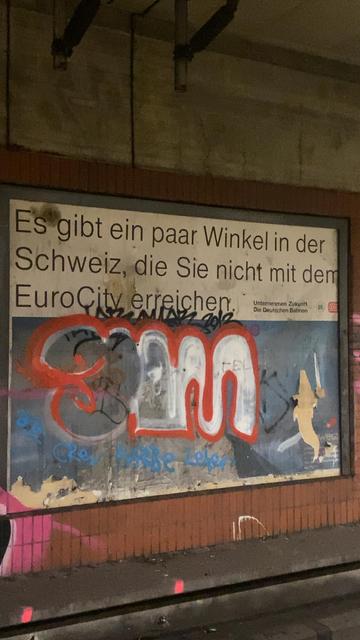 Bild einer Werbetafel, auf der steht: Es gibt ein paar Winkel in der Schweiz, die Sie nicht mit dem EuroCity erreichen.
Rechts unten steht: Unternehmen Zukunft Die Deutschen Bahnen und die Logos von Reichsbahn und Bundesbahn